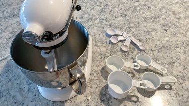 Orlando, FL USA - 5 Nisan 2020: Mutfak tezgahında yanında ölçü bardakları ve kaşıklar bulunan bir Kitchenaid Karıştırıcı.