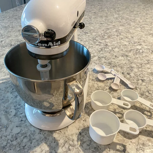 Orlando, FL USA - 5 Nisan 2020: Mutfak tezgahında yanında ölçü bardakları ve kaşıklar bulunan bir Kitchenaid Karıştırıcı.