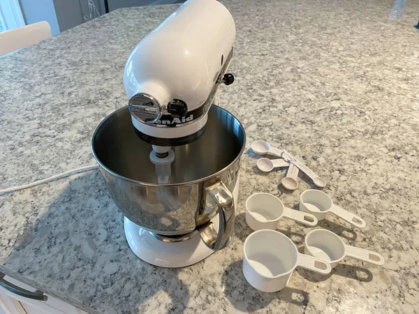 Orlando, FL USA - 5 Nisan 2020: Mutfak tezgahında yanında ölçü bardakları ve kaşıklar bulunan bir Kitchenaid Karıştırıcı.