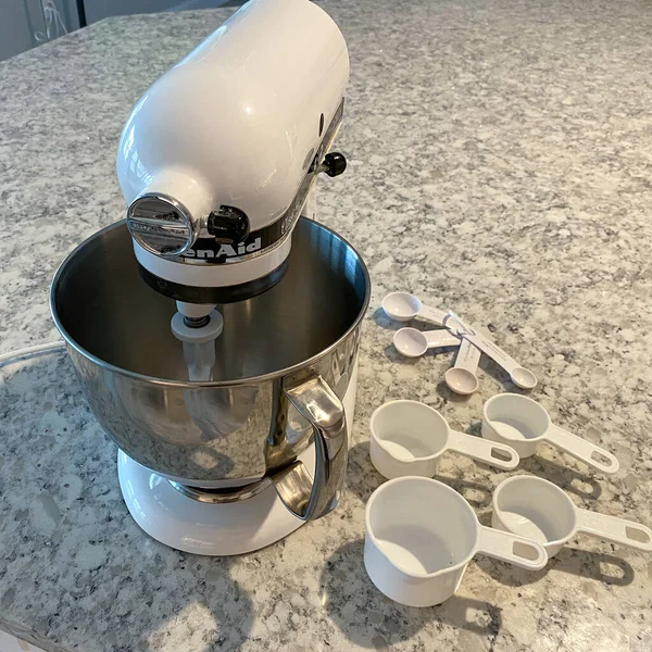 Orlando, FL USA - 5 Nisan 2020: Mutfak tezgahında yanında ölçü bardakları ve kaşıklar bulunan bir Kitchenaid Karıştırıcı.