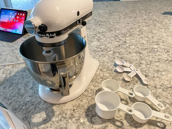 Orlando, FL USA - 5 Nisan 2020: Mutfak tezgahında yanında ölçü bardakları ve kaşıklar bulunan bir Kitchenaid Karıştırıcı.