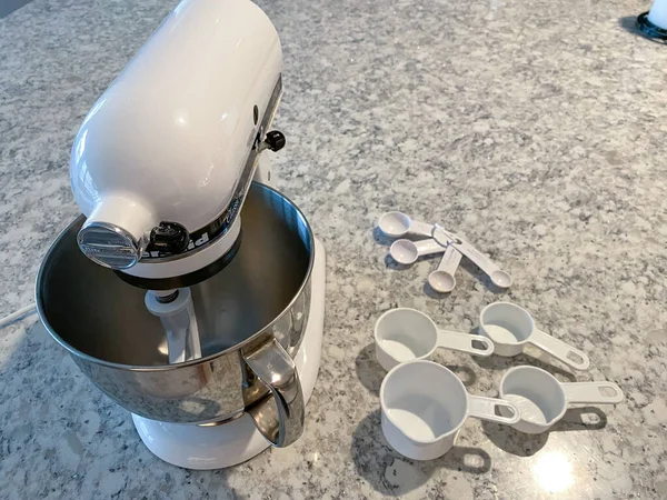Orlando, FL USA - 5 Nisan 2020: Mutfak tezgahında yanında ölçü bardakları ve kaşıklar bulunan bir Kitchenaid Karıştırıcı.
