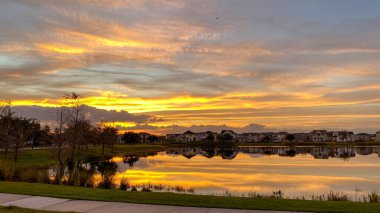 Güzel pembe, turuncu ve mavi gün batımı bir banliyö gölünde yansıyor..