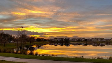 Güzel pembe, turuncu ve mavi gün batımı bir banliyö gölünde yansıyor..
