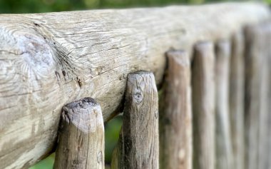 Botanik bahçesindeki köprüden gelen gri ahşap bir tırabzanın makrosu. Arka plan olarak kullanılabilecek bir bulanıklık var..