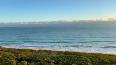 Atlantik Okyanusu 'nun hava manzarası. Dalgalar sahile vuruyor ve balıkçı tekneleri sabah erkenden yola çıkıyor..
