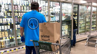 Orlando, FL USA - 24 Ocak 2021: Amazon Prime Fresh çalışanları Whole Foods marketinden alışveriş yaparak insanların evlerine götürmeleri için yiyecek seçiyorlar..