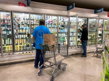 Orlando, FL USA - 24 Ocak 2021: Amazon Prime Fresh çalışanları Whole Foods marketinden alışveriş yaparak insanların evlerine götürmeleri için yiyecek seçiyorlar..