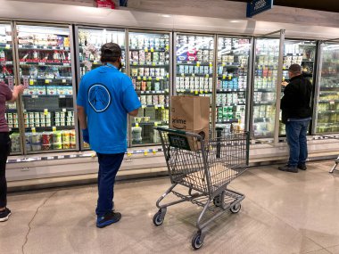 Orlando, FL USA - 24 Ocak 2021: Amazon Prime Fresh çalışanları Whole Foods marketinden alışveriş yaparak insanların evlerine götürmeleri için yiyecek seçiyorlar..