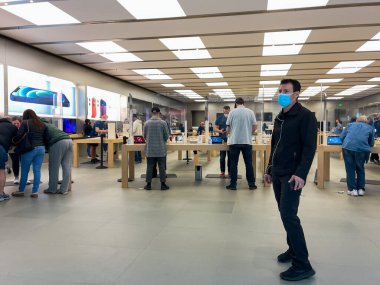 Orlando, FL USA - 5 Şubat 2021: Elma çalışanları koronavirüs salgınından dolayı yüz maskesi takarken pleksiglas kılıflı müşterileri bekliyor.