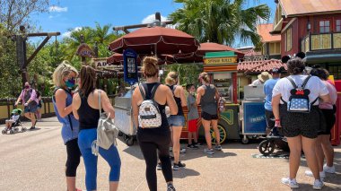 Orlando, FL USA - 2 Mayıs 2021: İnsanlar Disney World Magic Kingdom 'daki bir yemek arabasından Cheeseburger ve Pepperoni Spring Rolls almak için sırada bekliyorlar.