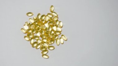 Bağışıklık sistemi sağlığını veya Omega 3 balık yağı kapsüllerini destekleyen D-3 vitamini yarı şeffaf jel kapsülleri yığınının üzerinde sağa dönüyor..