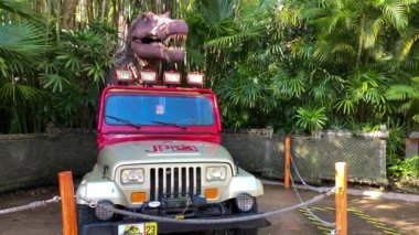Orlando, FL USA - 16 Temmuz 2021: Orlando, Florida 'daki Universal Stüdyoları tema parkında bir T-Rex dinozoruna ve Jurassic Park cipine yakınlaşmak.