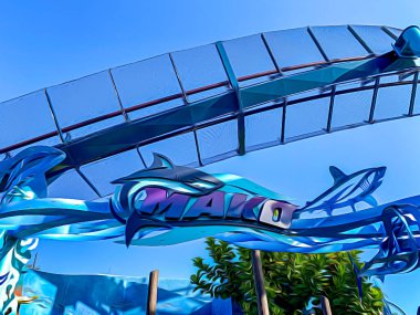 Orlando, FL USA - 25 Aralık 2019 SeaWorld Orlando Florida 'daki Mako Roller Coaster' ın parlak güneşli bir günde bir köpekbalığı logosu ve mavi su temalı girişinin bir gösterimi.