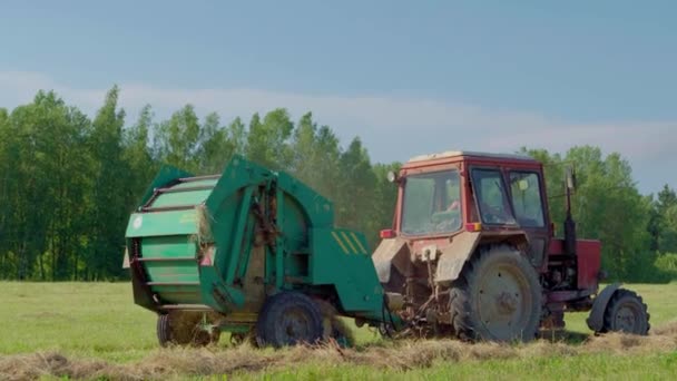 Круглий прес-підбирач під час збирання врожаю сільськогосподарських культур у польових умовах — стокове відео