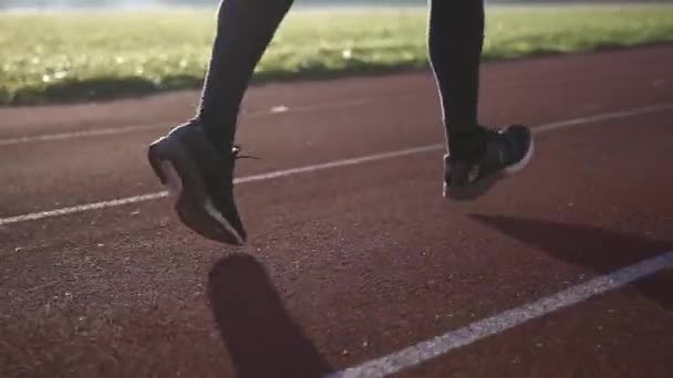 Κοντινό πλάνο των αθλητικών ποδιών σε μαύρα αθλητικά παπούτσια που τρέχουν στην πίστα στο γήπεδο. — Αρχείο Βίντεο
