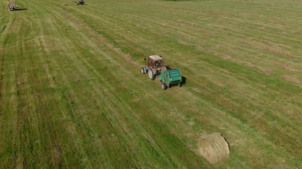 Landbouwmachines verzamelen droog stro op rollen en ronde grote balen. — Stockvideo