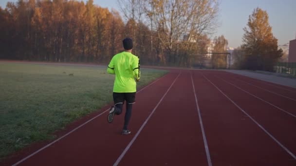 Atlétikai ember futó futás stadion pályán. — Stock videók