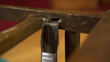 Eski ahşap bir sandalyeye fırçayla yapıştırıcı sürüyorum.