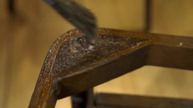 Eski ahşap bir sandalyeye fırçayla yapıştırıcı sürüyorum.