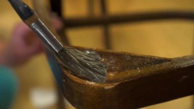 Eski ahşap bir sandalyeye fırçayla yapıştırıcı sürüyorum.