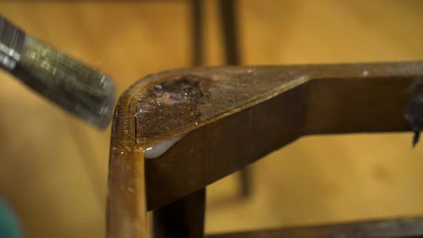 Ragasztó alkalmazása ecsettel egy régi fából készült lakkozott széken — Stock videók
