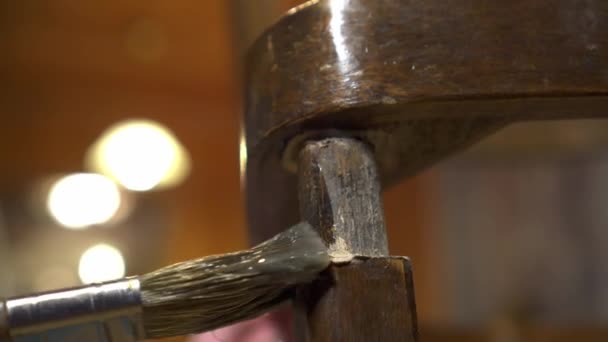 Нанесення клею пензлем на старий дерев'яний лакований стілець — стокове відео