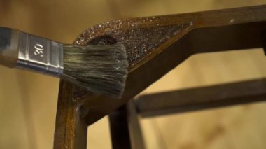 Eski ahşap bir sandalyeye fırçayla yapıştırıcı sürüyorum.