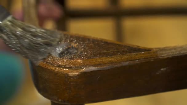 Применение клея кистью на старом деревянном лакированном стуле — стоковое видео