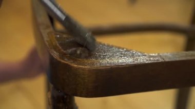 Eski ahşap bir sandalyeye fırçayla yapıştırıcı sürüyorum.