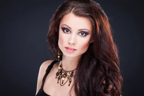 Portrait of young beautiful brunette woman in jewelry standing o — Stock Photo, Image