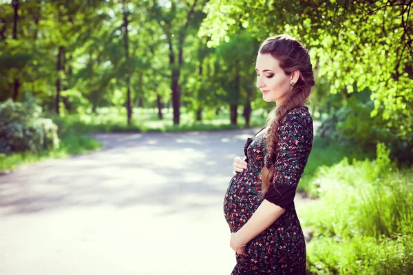 Joven mujer embarazada feliz con largo hermoso tress relajante un — Foto de Stock