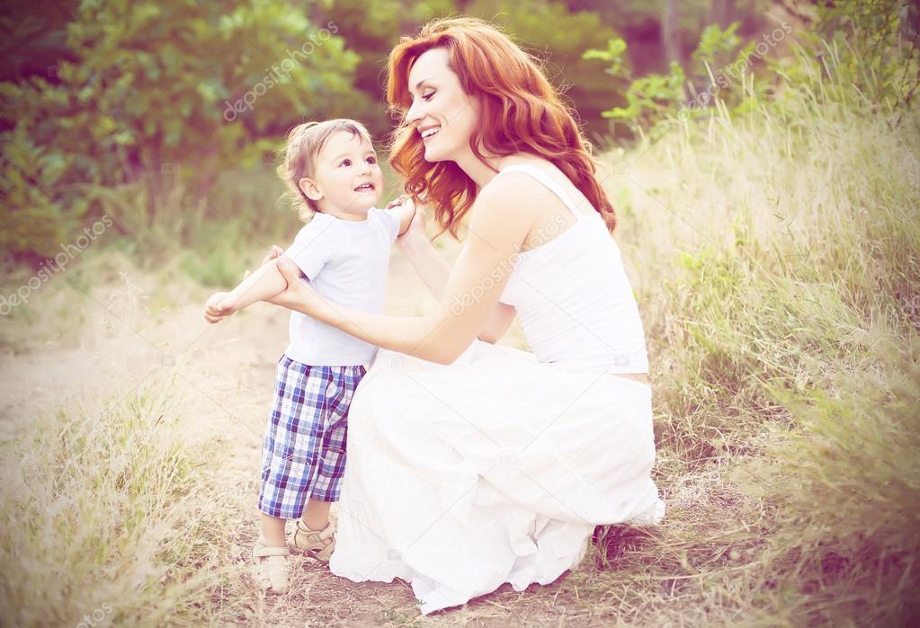 Mother with long curly red hair playing with her son in the park