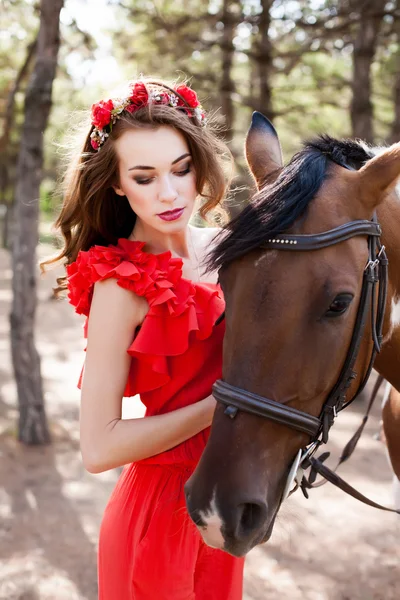 Belle jeune femme portant une robe rouge chevauchant un cheval au soleil s — Photo