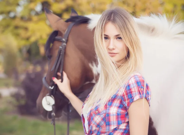 Belle jeune femme portant t-shirt et jeans chevauchant un cheval à — Photo