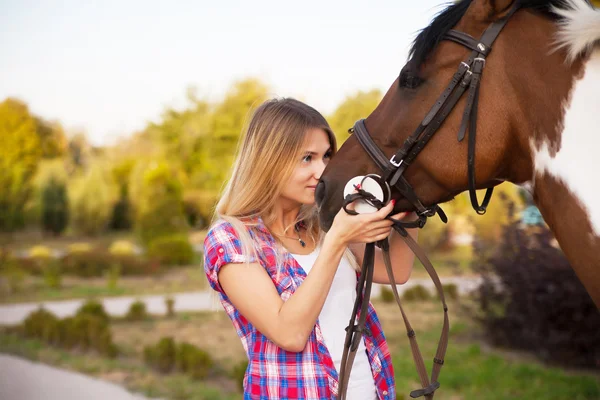 Schöne junge Frau in T-Shirt und Jeans beim Reiten auf einem Pferd — Stockfoto