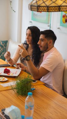 Genç aşıklar restoranda yemek yerken eğleniyorlar.