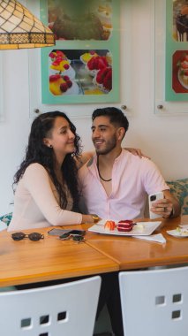 Genç aşıklar restoranda yemek yerken eğleniyorlar.