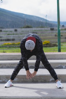 Genç adam parkta farklı ısınma ve kardiyo egzersizleri yapıyor..