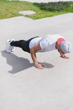 Genç adam parkta farklı ısınma ve kardiyo egzersizleri yapıyor..