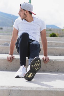 Genç adam parkta farklı ısınma ve kardiyo egzersizleri yapıyor..