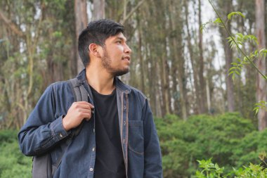 Ormanda yürüyen genç adam. Sırt çantası, cep telefonu kaydı ve fotoğraf çekerek..