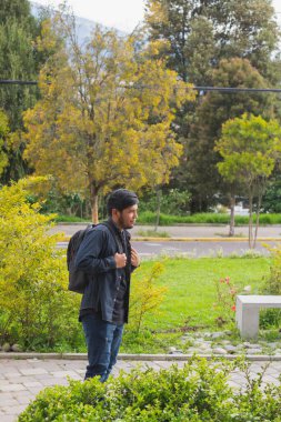 Ormanda yürüyen genç adam. Sırt çantası, cep telefonu kaydı ve fotoğraf çekerek..