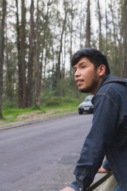 Ormanda yürüyen genç adam. Sırt çantası, cep telefonu kaydı ve fotoğraf çekerek..