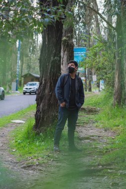 Ormanda yürüyen genç adam. Sırt çantası, cep telefonu kaydı ve fotoğraf çekerek..