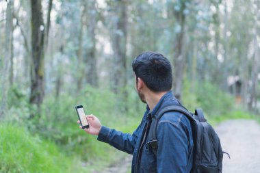 Ormanda yürüyen genç adam selfie çekiyor. Arkadaşlarına göstermek için..