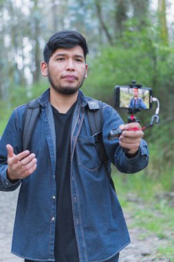 Ormanda yürüyen genç adam selfie çekiyor. Arkadaşlarına göstermek için..