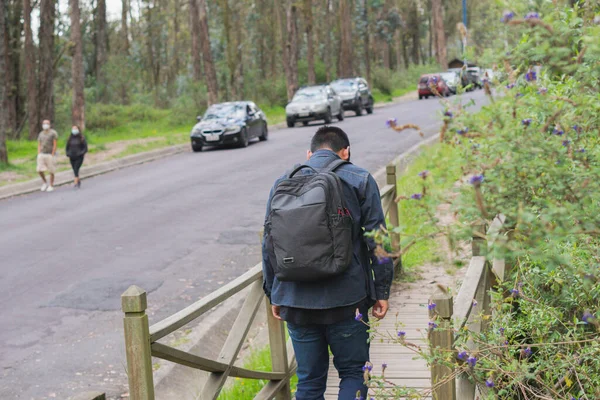 Young man walking in the woods. With his backpack and cell phone recording and taking pictures.