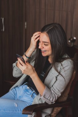 Cep telefonunu kontrol eden ve yazan genç bir kadın. Sosyal ağlarını ve fotoğraflarını kontrol ediyorum..