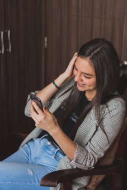 Cep telefonunu kontrol eden ve yazan genç bir kadın. Sosyal ağlarını ve fotoğraflarını kontrol ediyorum..